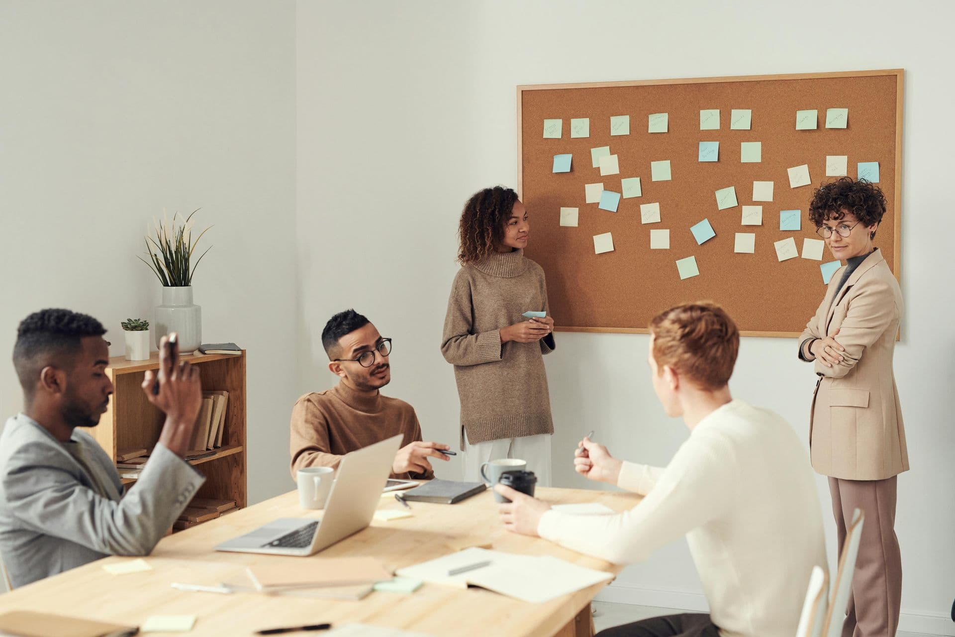 People gathered around a table with a board with sticky notes on depicting a workshop setting